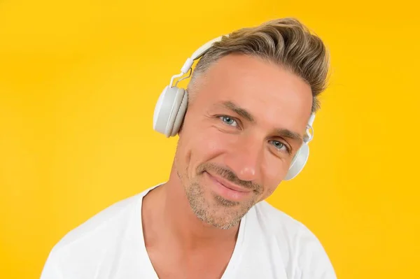 Ακούτε προσεκτικά. Μεσήλικας άντρας φοράει ακουστικά κίτρινο φόντο. Αγγλική σχολή. Μαθαίνω ξένη γλώσσα. Μαθήματα ήχου. Ακουστική εξάσκηση. Σύγχρονη εκπαίδευση. Ακουστική τεχνολογία — Φωτογραφία Αρχείου