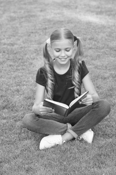 För att läsa missbrukare. Glad barn läsa bok om grönt gräs. Liten flicka tycker om att läsa sommar utomhus. Läslista för sommaren. Utvecklar fantasin. Läsa andas för sinnet — Stockfoto