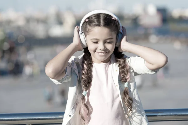 Bambina ascoltando musica godere di canzone preferita. Ragazza con cuffie sfondo urbano. L'influenza positiva della musica. Bambino ragazza godendo di musica auricolari moderni. Infanzia e musica adolescenziale gusto — Foto Stock