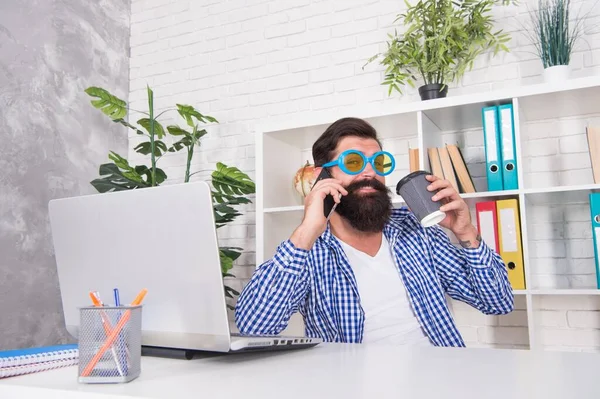 Cool freelancer in fancy glasses talk on mobile phone drinking coffee in modern office, morning — Stok fotoğraf