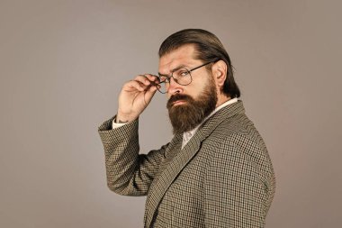 Hırslı bir manken. Gri arka planda duran yakışıklı adam. Ciddi sakallı iş adamı. Modern görünümlü şık, olgun bir adam. Erkek ceketi dolabı. Şık bir adam gözlük takıyor.