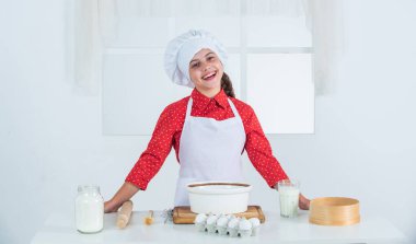 Kız un ve yumurtadan hamur yapıyor. Diyet ve sağlık. Aşçılık okulu. Geleneksel mutfak. Çocuk mutfakta yemekle eğleniyor. Çocuk ve pişirme. Sağlıklı beslenme ve yaşam tarzı kavramı