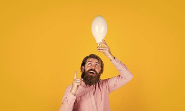 Yaratıcılık kavramı. Adam sadece ilham verdi. Elektrik ekonomisi. Zeki hippi. yaratıcı ilham. Yolunu aydınlat. Ampullü sakallı adam. Gülümseyen adam büyük lambayı tut. Yeni bir fikrim var.
