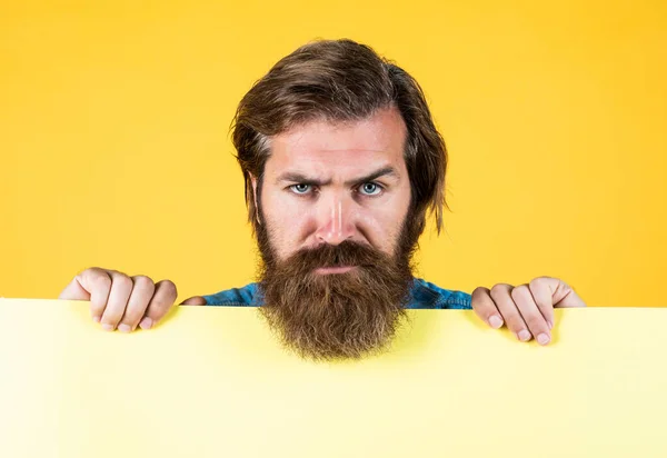 Serious bearded man. barbershop and hairdresser. We can help to community. brutal caucasian hipster hold paper shit, copy space. human emotions. unshaven guy with groomed long hair — Stock Photo, Image