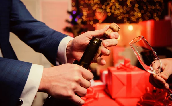 Vier Nieuwjaar met champagne. Handen openen champagne fles en houden glas kerst decoraties achtergrond. Proost concept. Laatste minuut voor Nieuwjaar. Champagne of mousserende wijn drinken — Stockfoto