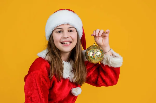快乐的圣诞女孩戴着红色的圣诞老人帽，装束着树的装饰，装饰着 — 图库照片