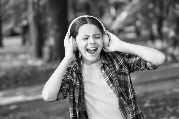 Everything but music. Happy girl sing to music summer outdoors. Little child wear headphones playing music. Modern life. New technology. Summer holidays. Leisure and pleasure. Give in to the groove