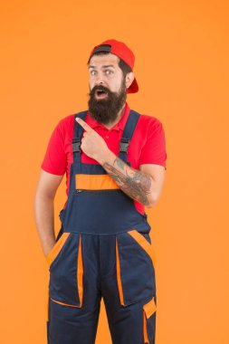 Sakallı, olgun bir işçi üniformalı, parmakla işaret ediyor.