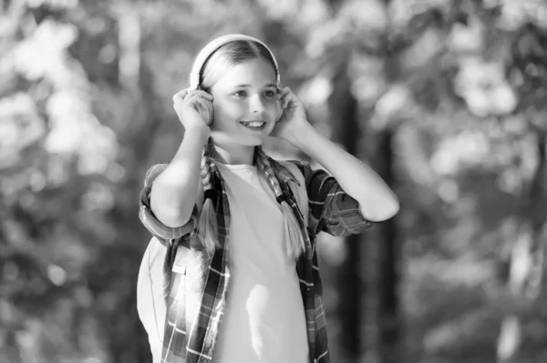 En väsentlig del av det moderna livet. Liten flicka bär hörlurar naturligt utomhus. Små barn lyssnar på musik. Hej-Fi-ljud. Digitalt ljud. Modern teknik. Sommarsemester och resor. Modern livsstil — Stockfoto