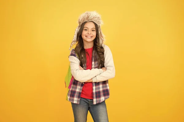 学校の活動の後。学校に戻って。女子高生バックパック黄色の背景。今週は授業なし。子供の弟子だ。学校での冬のイベント。小さな女の子は耳フラップの帽子を着用。冬休みの時間 — ストック写真