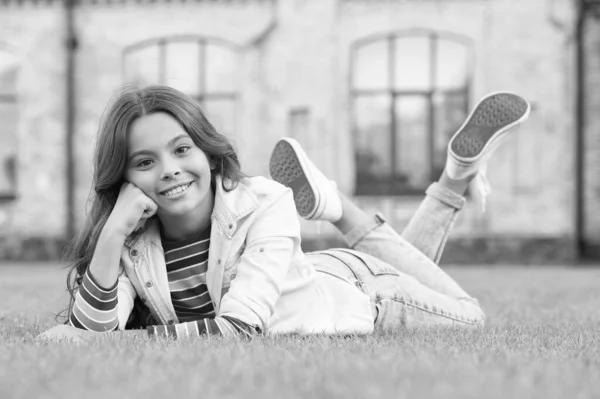 Una mirada de perfección. Chica feliz descansar en la hierba al aire libre. Belleza mirada de niño. Mirada de Vogue. Mirada de moda casual. Ropa de niños. Ven, relájate y disfruta — Foto de Stock