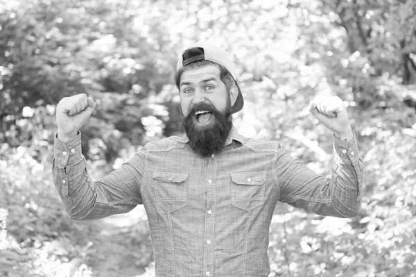 Los bosques están llamando. morena barbudo hombre llevar gorra en el bosque en el fondo de los árboles. brutal morena hombre celebrar el éxito. chico maduro con barba en madera. cálido día de verano. hombre barbudo mirada feliz — Foto de Stock