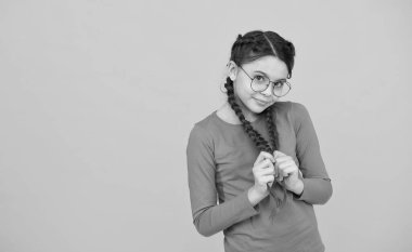 Utangaçtır. Olumlu duygular. Gözlük takıyor çünkü gözleri iyi görmüyor. Gözlüklü mutlu kız portresi. Havalı saç stili olan güzel, gülümseyen bir kız. zeki görünümlü çocuk sarı arka plan