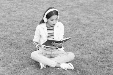 Olmak için harika bir yer. Dijital hayatta yeni teknoloji. Bilgi günü. Gelecekteki okul eğitimi. Yeşil çimenler üzerine kitabı olan genç bir kız. Küçük tatlı kız kitap okuyor. çocuklar için edebiyat eğitimi