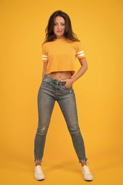 Güzellik ve makyaj. Uzun saçlı güzel bir kız. Moda ve tarz. Dar kot ona yakışıyor. Kendine güven en iyi ekiptir. Seksi kız sarı arka plan. Seksi bir kız. Sıradan tarzda şehvetli bir kız.