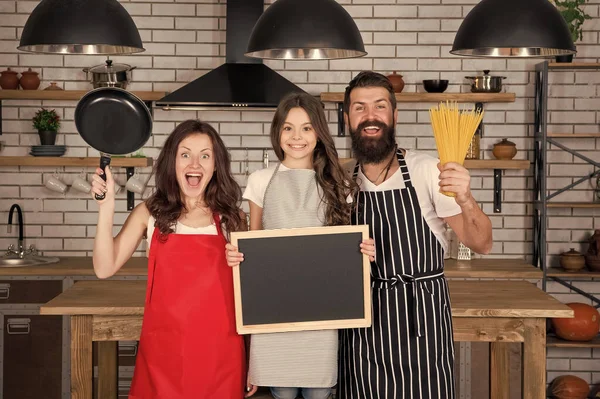 Familjetradition. Lycklig familj i köket. Trevligt att träffas. Recept på perfekt familjemiddag. Mor och far med en liten flicka som håller tavlan kopierad. Liten flicka med föräldrar matlagning — Stockfoto