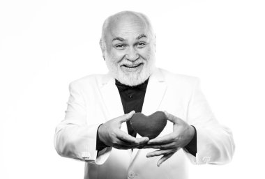 Sağlık hizmetleri. Kalp krizini önlüyor. Yaşlı kel sakallı adam elinde kırmızı oyuncak bir kalp tutuyor. Sağlıklı bir hayat. Sevgililer günü kalbi olan olgun bir adam. Kalp ve sağlık sigortası. Teşhis ve tedavi