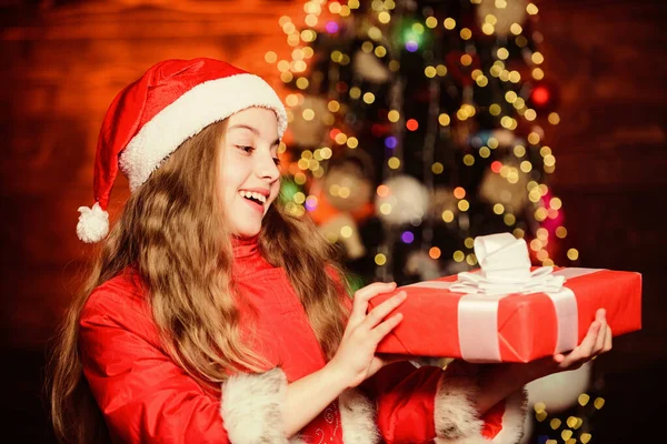 Feliz año nuevo. Niño elfo con caja de regalo. Árbol de Navidad. Felices fiestas. Niña con sombrero rojo. Feliz navidad. Santa Claus niña. Chriatmas interior. En Navidad. Sé positivo. — Foto de Stock