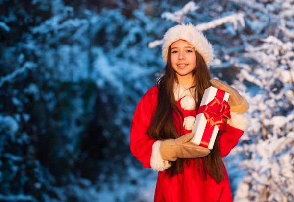 Es hora de milagros. Generoso Santa Claus. Niño feliz chica al aire libre naturaleza nevada. Feliz navidad. Concepto de infancia feliz. Felicidad y alegría. Sombrero de Santa Claus. Regalos de Santa. Mañana de Navidad helada —  Fotos de Stock