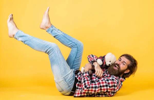 Chico barbudo guapo feliz con la cara sin afeitar y el peinado elegante usar ropa casual y jugar con juguetes de oso, felicidad —  Fotos de Stock