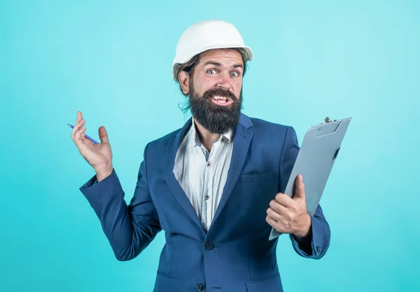 Brutális borotválatlan fickó formális viseletben és kemény kalapban az építkezésen, üzlet — Stock Fotó