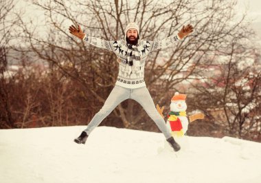 Şuna bir bak. Kış tatili açık havada. Soğuk havada sıcak kazak. Adam karla oynuyor. Sakallı adam kardan adam yapar. Mutlu hipster Noel 'i kutlamaya hazır. Kış mevsimi aktivitesi. Noel 'i