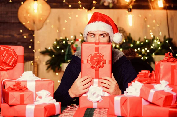 Hipster prepared gifts for family. Home is heart of holidays. Wrapped gifts with ribbons and bows. Man santa claus hat celebrate new year. Generous new year. Lot of gifts. Happy winter holidays