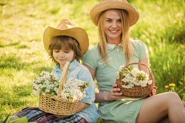 Le bonheur maternel. Famille Cowboy ramassant des fleurs dans des paniers. Fleurs sauvages dans les champs. Joyeuses fêtes. Mère et mignon fils portent des chapeaux. Ferme familiale. Beau fond de nature familiale. Vacances de printemps — Photo