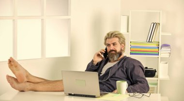 İş başarısı. Teknoloji. Evde dizüstü bilgisayar kullanan yakışıklı adam. Kendini karantinaya al. Serene yalınayak dinleniyor, evde hayal kuruyor. Bilgisayarla uzaktan kumanda. Evde kalırken ağ oluşturma