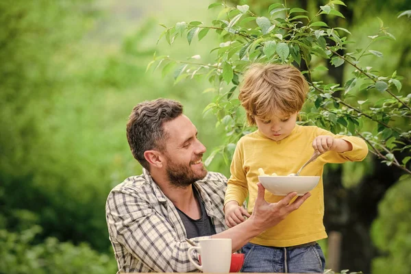 Best weekend ever. healthy food and dieting. Dairy products. family dinner time. Morning breakfast. Vegetarian diet. happy fathers day. Little boy with dad eat cereal. father and son eating outdoor — Stock Photo, Image