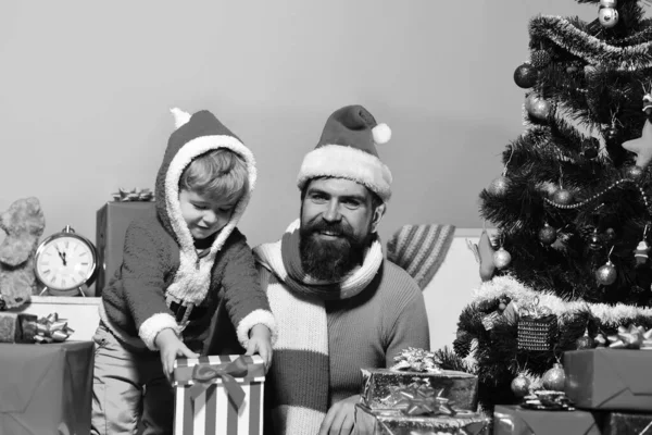 Kerstman en kleine assistent onder geschenkdozen in de buurt van kerstboom. — Stockfoto