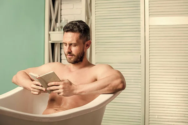 Macho profiter du livre dans le bain. Homme sexy dans la salle de bain lecture. Macho nue dans la baignoire. Concept de sexe et relaxation. l'homme a un corps musclé. Laver soigneusement la mousse avec de l'eau. amoureux du livre. Un vrai bonheur — Photo