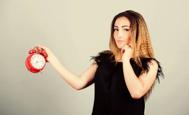 Zaman yönetimi. Dakiklik ve disiplin. Kadının elinde kırmızı alarm saati var. Sürenin dolmasına kadar zaman sayıyorum. Güzel kız zamanını yönetiyor. Fazla çalışmak ya da geç kalmak. Zamanlama sorunu. Vakit geldi. Birkaç dakika.