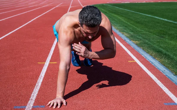 Muskulöser Kerl macht Liegestütze in Planke im Freiluftstadion, Sport — Stockfoto