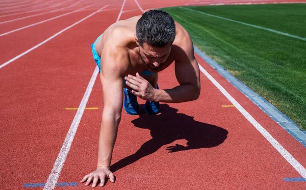 Gespierde man doet push-ups staan in plank in outdoor stadion, sport — Stockfoto