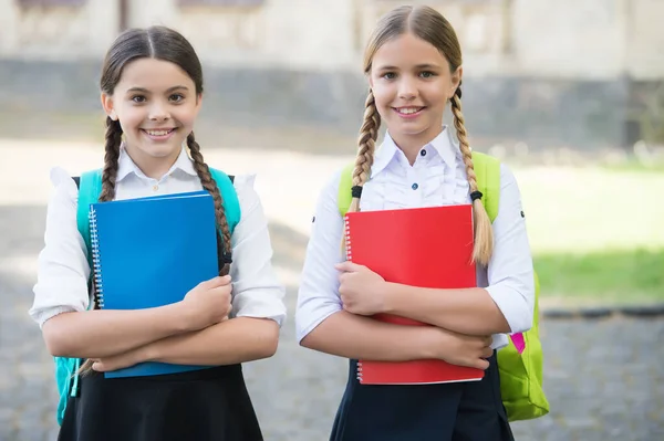 Niños felices en uniformes escolares tienen libros de estudio al aire libre, desarrollo —  Fotos de Stock