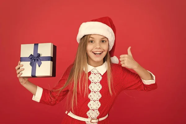 Sorpresa para ella. Felices fiestas de invierno. Regalo de apertura de niña pequeña. Año nuevo. Regalo de Santa Claus. Niña pequeña recibió un regalo. Regala Navidad. Momento mágico. Alegre niño traje de carnaval fondo rojo —  Fotos de Stock