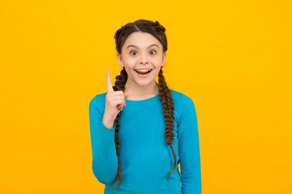 Inspirada menina adolescente feliz com cabelo trançado tem uma ideia sobre fundo amarelo, criatividade — Fotografia de Stock