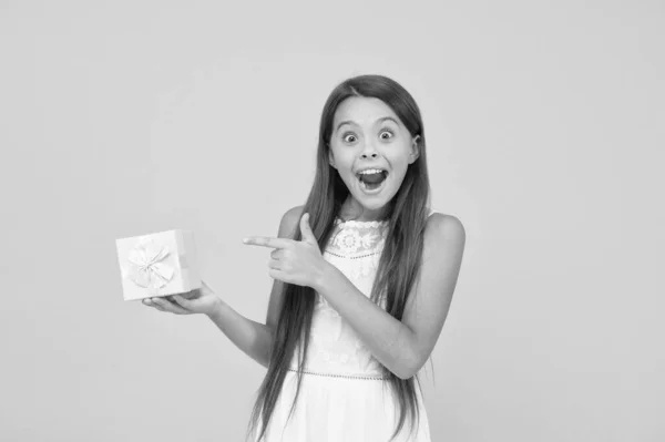 Perfecto. sorprendida niña sostiene caja de regalo. concepto de día de boxeo. niño pequeño sobre fondo amarillo. ventas de compras de vacaciones. caja de belleza. sorpresa para el cumpleaños. muy esperado presente. feliz infancia —  Fotos de Stock