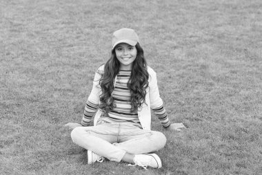 Fotoğraf için poz vermek. Parktaki güzel öğrenci kız. Şirin, kendine güvenen liseli kız yeşil çimlerde rahatlıyor. Mutlu çocukluk. Okula dönüyorum. Küçük kız günlük kıyafetler giyer. güzellik ve moda