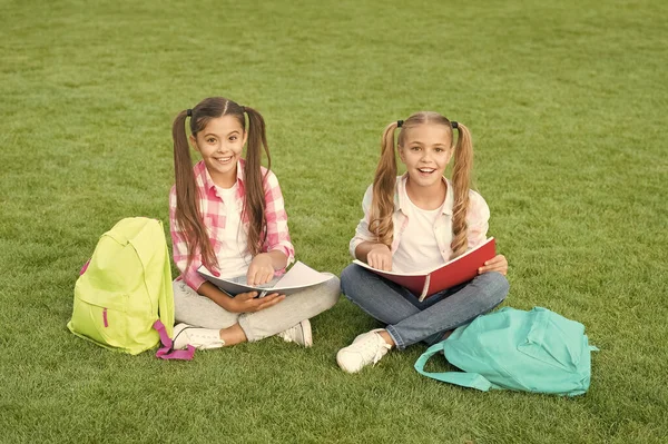 Des filles ludiques. littérature pour les filles. faire des devoirs ensemble. trouver quelque chose d'intéressant dans le livre. prendre des notes. passer du temps libre après l'école. petits amis enfants se détendre sur l'herbe. retour à l'école — Photo