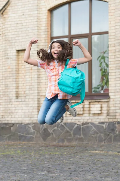Happy energiczny dzieciak skakać z torbą szkolną w stylu casual na szkolnym podwórku, święta — Zdjęcie stockowe