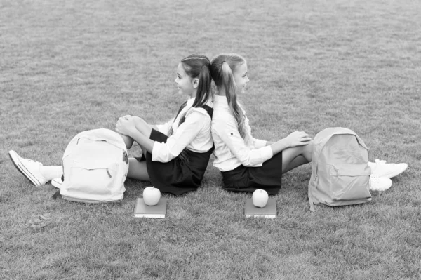 Venez, détendez-vous et profitez. Les écolières s'assoient sur l'herbe verte. Les filles heureuses portent l'uniforme scolaire. Je retourne à l'école. Regarde la beauté des petites filles. Petites filles en queue de cochon. Salon de coiffure. La beauté réside dans un esprit sain — Photo