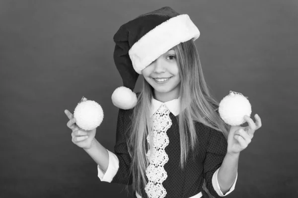 Мбаппе в хорошем списке Санта. Happy child hold Xmas tree balls. Маленькая девочка улыбается с видом Санты. Празднуйте Рождество и Новый год в стиле Санты. Сочельник. Новогодний праздник. Санта-вечеринка — стоковое фото