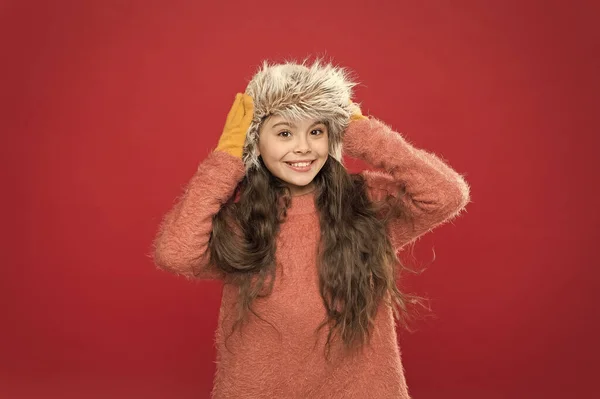Küçük moda anlayışı. Çok rahat hissediyorum. Çocuk uzun saçlı yumuşak şapkalı. Kış moda konsepti. Soğuk kış havası için sıcak şapka. Çocuk gülümsemesi kırmızı arka plan. Yumuşak tüylü aksesuar. Kış mevsimi — Stok fotoğraf