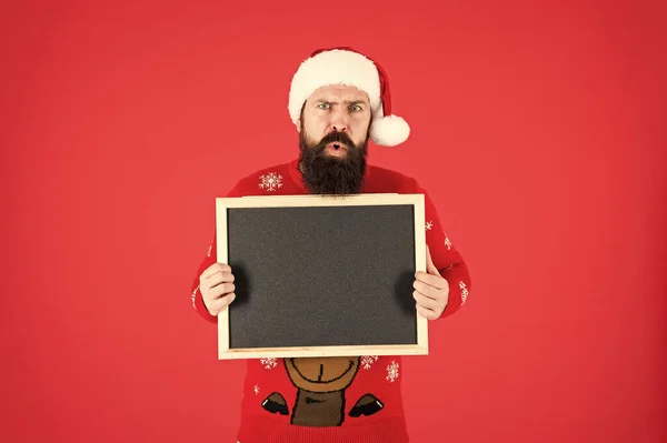 Kerstmis komt eraan. Hipster houdt kerstman verlanglijstje schoolbord. Een man met baard en blanco reclamebord. Schoolbord voor de kerstman schoolinformatie. Schoolbord voor Nieuwjaarsreclame, kopieerruimte — Stockfoto