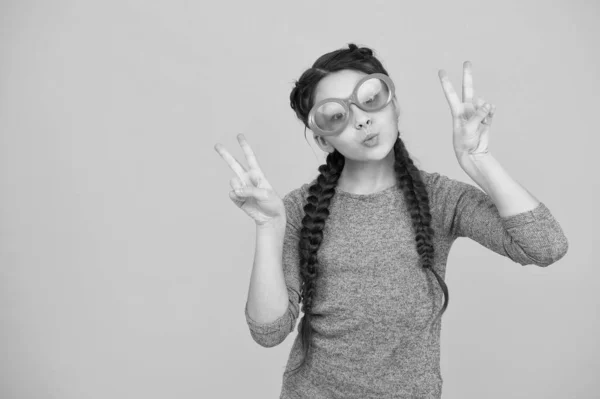 Montrant le geste de la pièce. Enfant mode et beauté. petite fille qui a l'air cool. bonheur d'enfance. beaux cheveux longs tressés. tresses et tresses élégantes. fête amusante. drôle adolescent fille dans lunettes — Photo