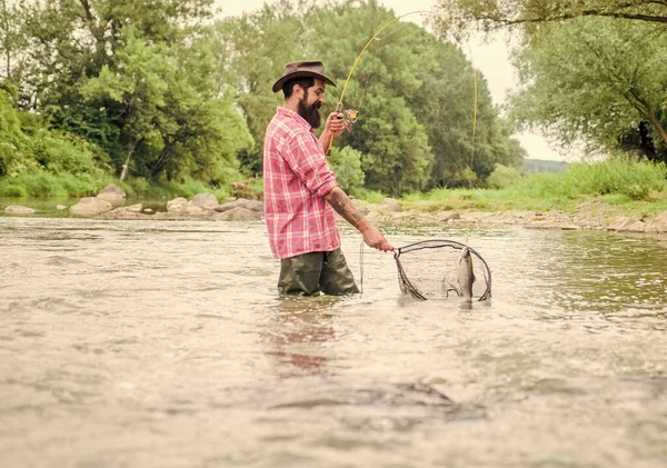 Hobby di pesca. Se il pesce regolarmente si sa come la pesca gratificante e rilassante è. La pesca è uno sport all'aperto ricreativo accessibile stupefacente. Barbuto brutale pescatore cattura pesce trota con rete — Foto Stock