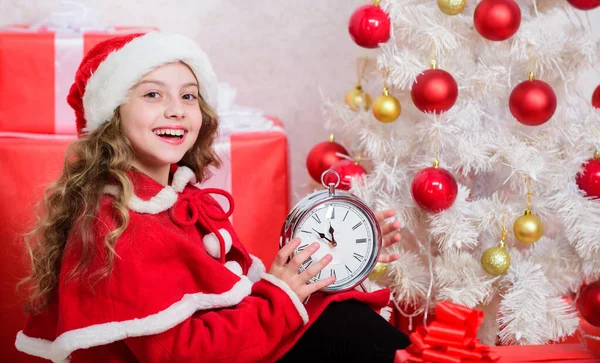 À espera de um milagre. Contagem regressiva de ano novo. Plano de véspera de ano novo de última hora. Feliz conceito de Natal. Último minuto até à meia-noite. Menina miúdo santa chapéu segurar relógio animado feliz cara contando o tempo para o ano novo — Fotografia de Stock