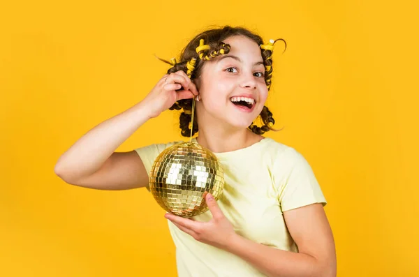 Discobal decoratie. Mooi meisje met discobal. Mode meisje poseren in krulspelden op de gele muur. Zaterdagavond en discobal. Babyfeestje. Laten we lol maken op retro party. vakantie-objecten — Stockfoto